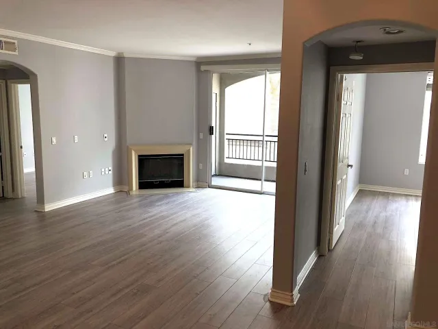 an empty room with wooden floor fireplace and windows
