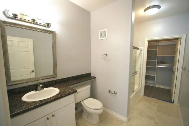 a bathroom with a granite countertop sink toilet and mirror