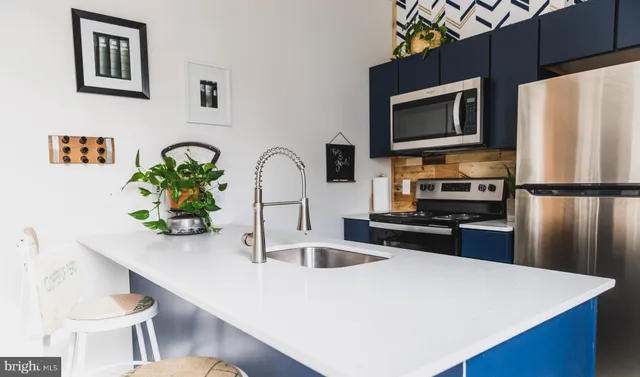 a kitchen with stainless steel appliances a stove a microwave a sink a refrigerator and white cabinets