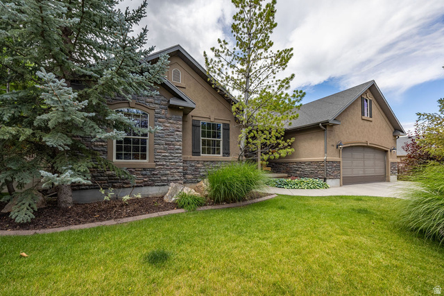 Exterior featuring a stone and stucco facade, an arched garage door, and a concrete driveway