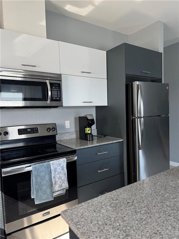 2022 Summerland Lane, Unit 4 Edinburg, TX 78541 - Photo 5 of 31 a kitchen with granite countertop wooden cabinets and stainless steel appliances