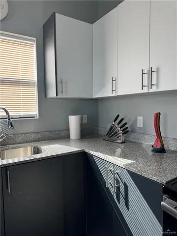 a kitchen with granite countertop a sink a stove and cabinets