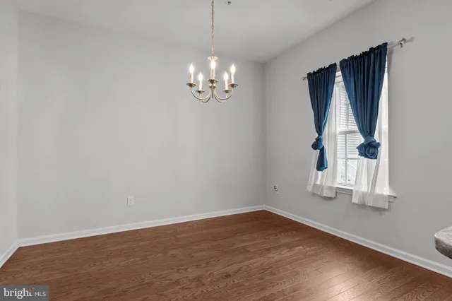 a view of empty room with wooden floor and window