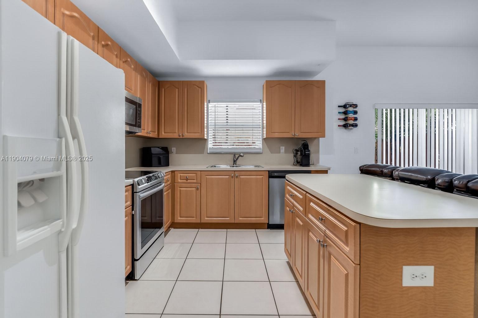 22232 Southwest 88th Path Cutler Bay, FL 33190 - Photo 19 of 72 a kitchen with stainless steel appliances granite countertop a sink a stove a refrigerator a washer dryer and white cabinets