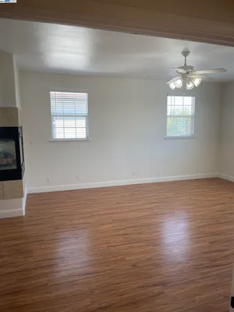 an empty room with wooden floor chandelier and windows
