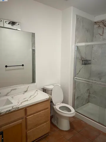 a bathroom with a granite countertop toilet a sink and a mirror