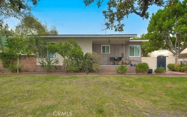 a view of a house with a garden and a tree