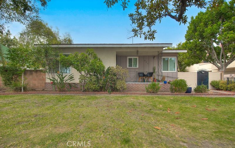 a view of a house with a garden and a tree