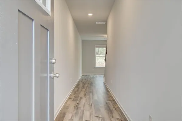 a view of a hallway with wooden floor and a bathroom