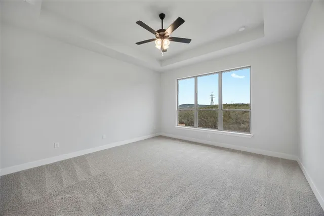 an empty room with chandelier fan and windows