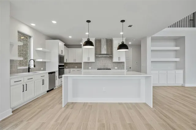 a large white kitchen with kitchen island a sink stainless steel appliances and cabinets