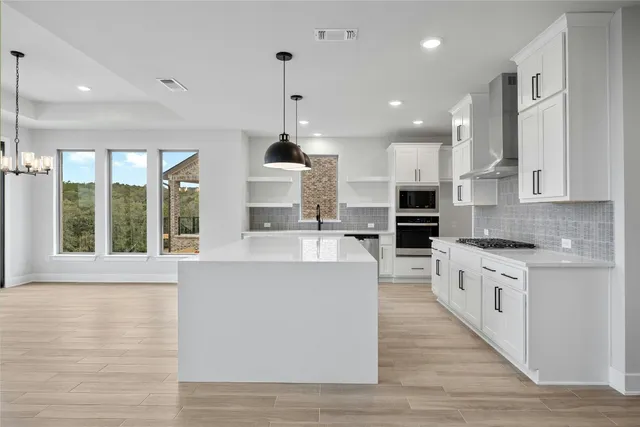 a large kitchen with stainless steel appliances lots of counter space and windows