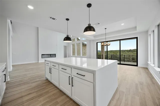 a large white kitchen with stainless steel appliances granite countertop a stove and a wooden floor