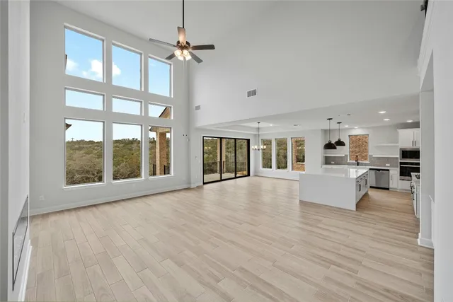 a view of an empty room with wooden floor and a kitchen