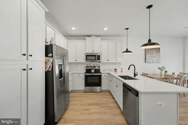 a kitchen with stainless steel appliances kitchen island granite countertop a refrigerator a sink a stove and oven with wooden floor