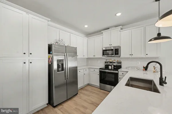 a kitchen with stainless steel appliances granite countertop a refrigerator a sink a stove and white cabinets