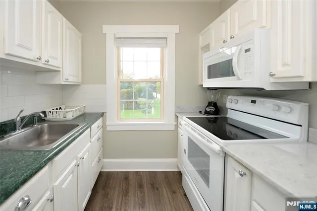 a kitchen with granite countertop a sink stove and cabinets