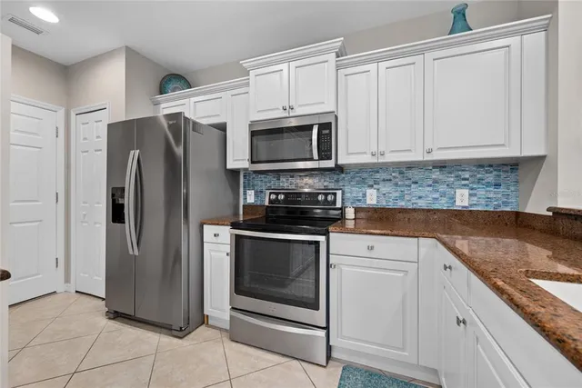 a kitchen with granite countertop a refrigerator stove and microwave