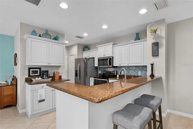 a kitchen with granite countertop a sink stainless steel appliances and white cabinets