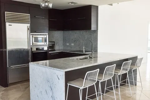 a kitchen with kitchen island a counter top space appliances and a sink
