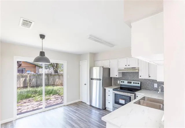 a kitchen with stainless steel appliances a stove a refrigerator a sink and white cabinets