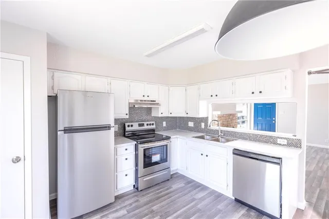 a kitchen with stainless steel appliances a refrigerator a stove a sink and white cabinets