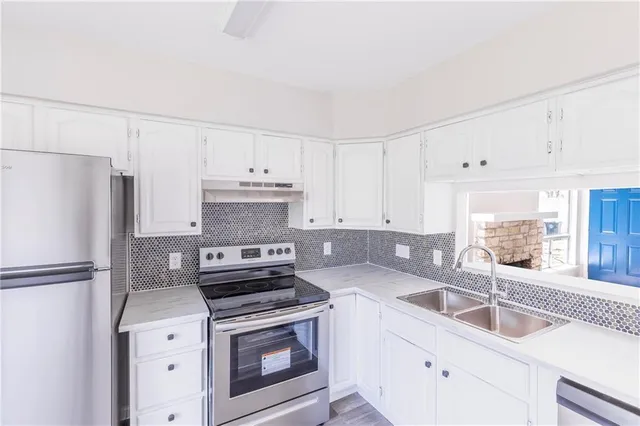 a kitchen with granite countertop a sink stove and refrigerator