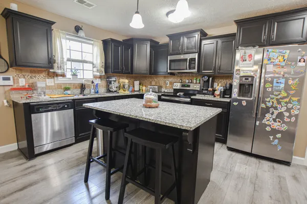 a kitchen with granite countertop a sink stove and refrigerator