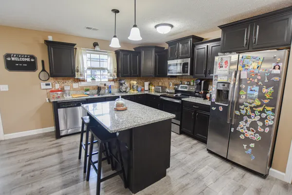 a kitchen with granite countertop stainless steel appliances a sink stove and refrigerator