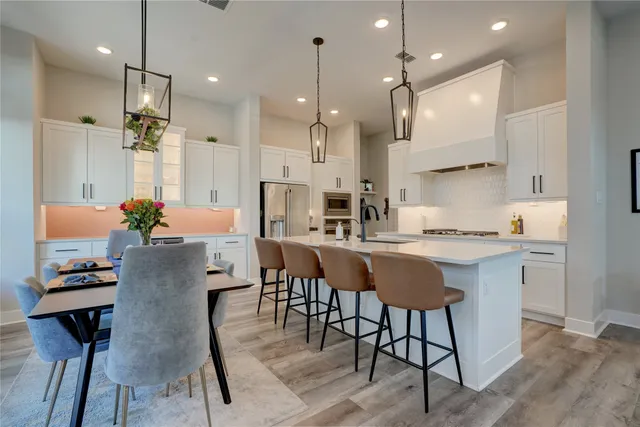 a kitchen with kitchen island stainless steel appliances a stove a sink a oven a center island and chairs