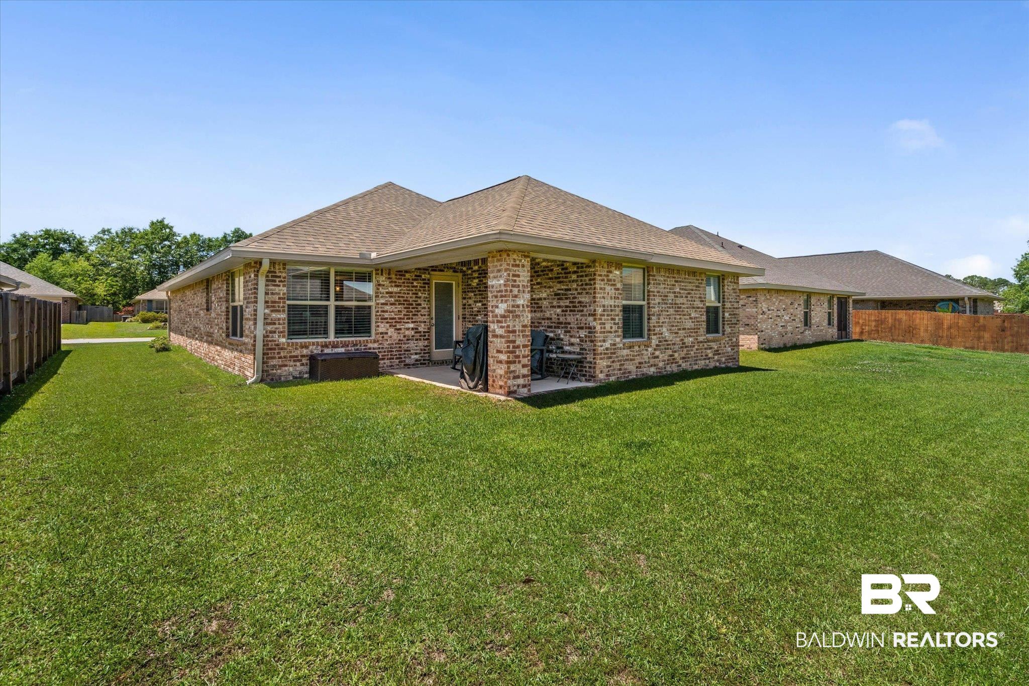 22420 Respite Lane Foley, AL 36535 - Photo 20 of 35 Expansive backyard featuring a brick exterior, covered patio, multiple windows, a wood fence, and a pitched roof
