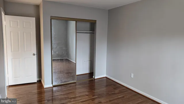 an empty room with wooden floor & closet area
