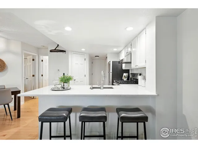 a kitchen with stainless steel appliances kitchen island granite countertop a table chairs in it and white cabinets
