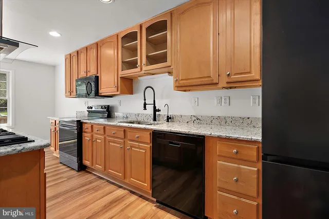 a large kitchen with stainless steel appliances granite countertop a stove top oven a sink dishwasher and a microwave oven with wooden floor