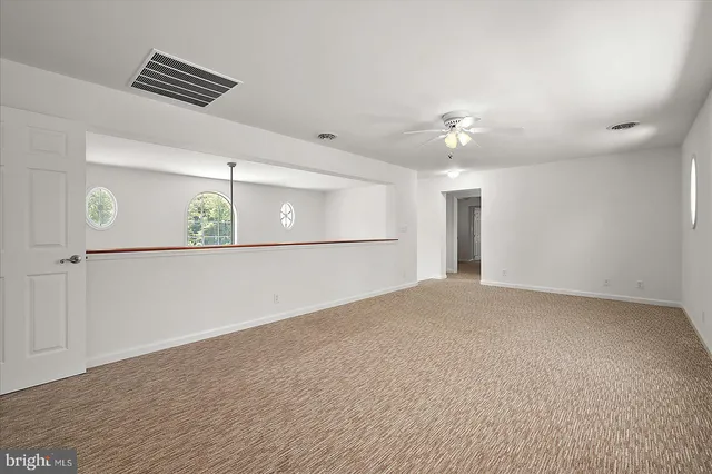 an empty room with a window and a fan