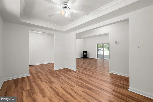 a view of empty room with wooden floor and fan