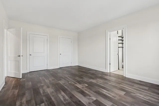 a view of an empty room with closet and wooden floor