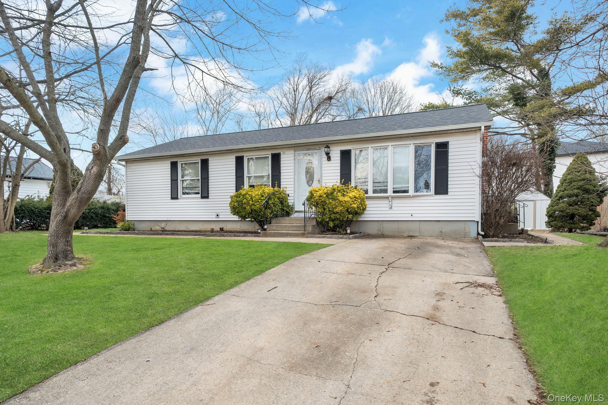 Ranch-style home featuring a front lawn and roof with shingles