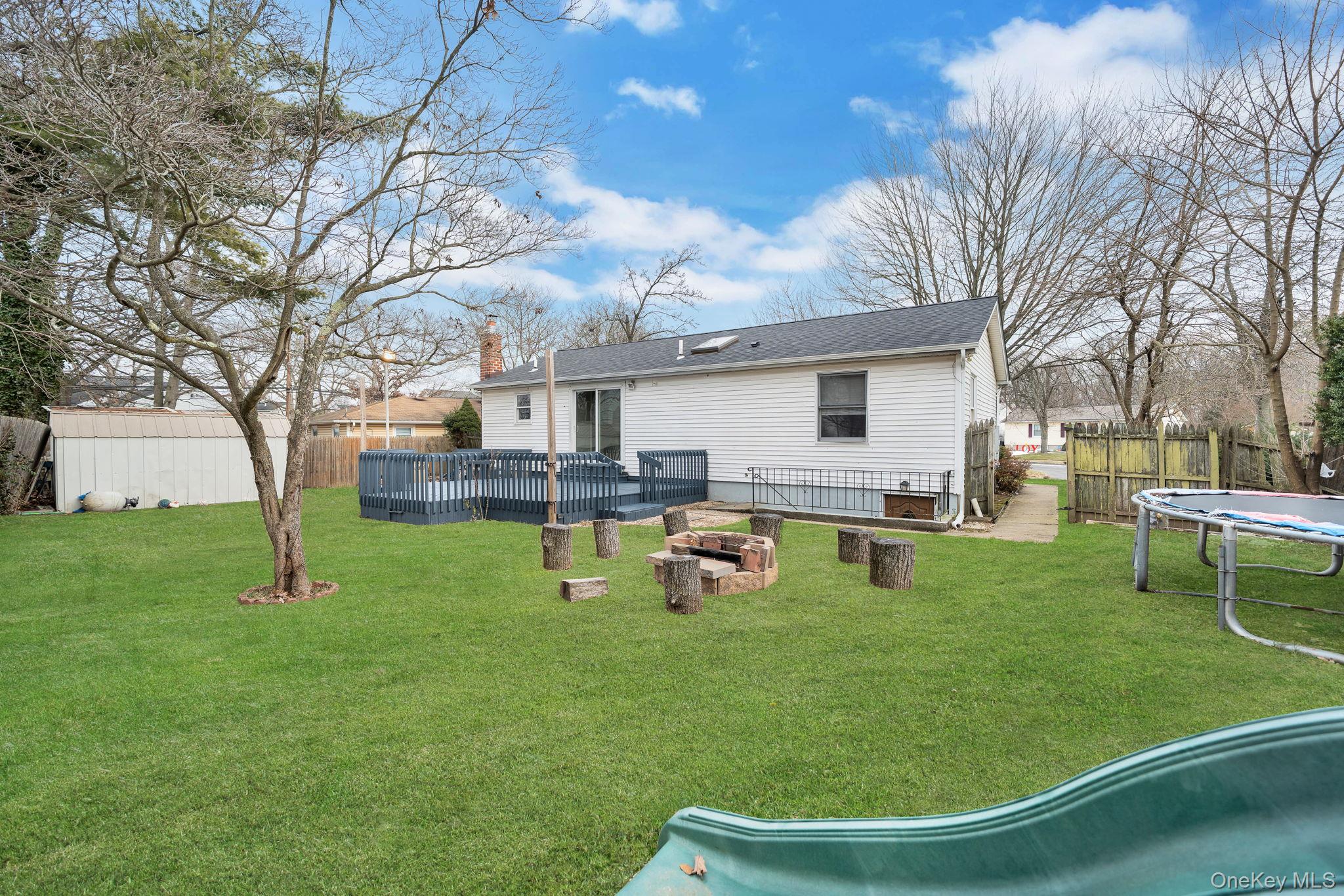 7 Kristin Court Bay Shore, NY 11706 - Photo 3 of 14 Back of property featuring a trampoline, a wooden deck, a chimney, and roof with shingles
