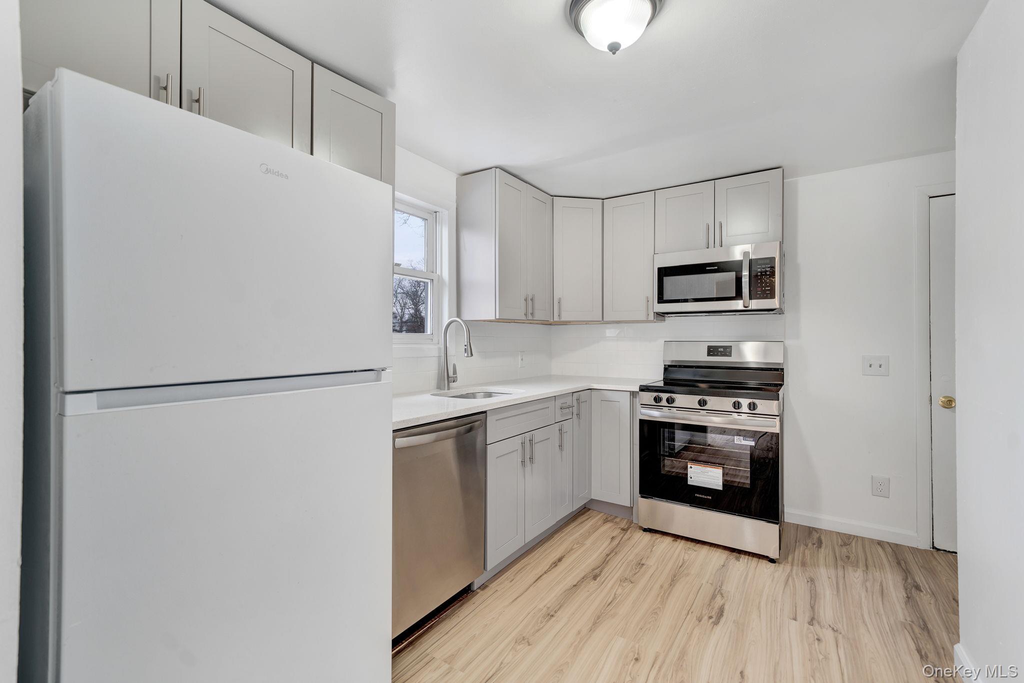 7 Kristin Court Bay Shore, NY 11706 - Photo 8 of 14 Kitchen featuring stainless steel appliances, light wood-style floors, and gray cabinets