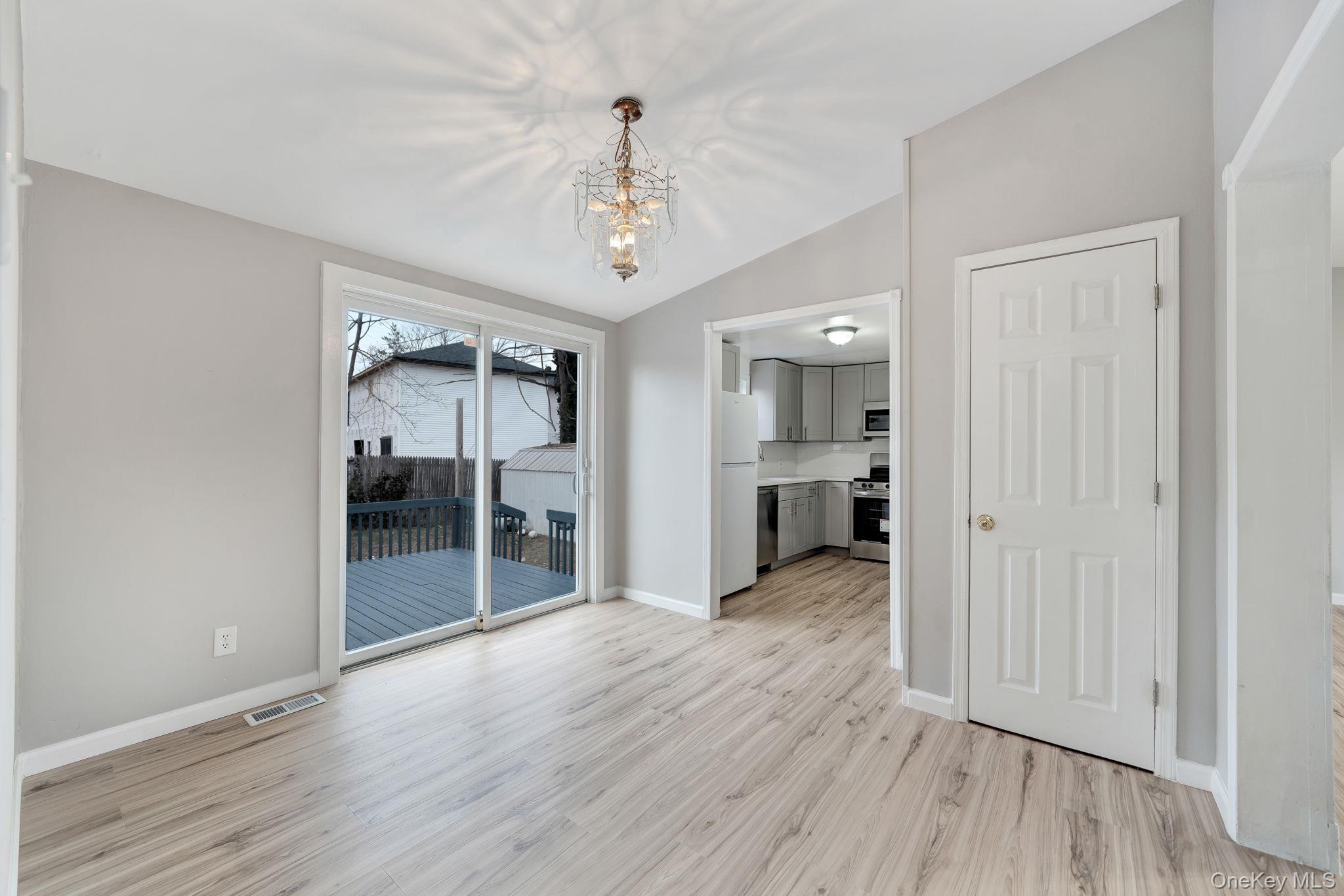 7 Kristin Court Bay Shore, NY 11706 - Photo 9 of 14 Unfurnished dining area with vaulted ceiling, a chandelier, and light wood-type flooring