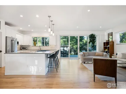 a living room with stainless steel appliances kitchen island granite countertop furniture and a large window