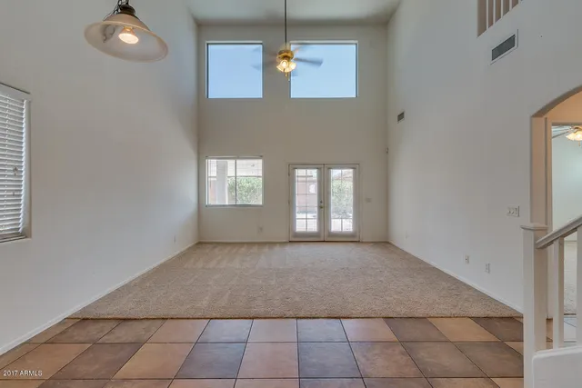 an empty room with windows and ceiling fan
