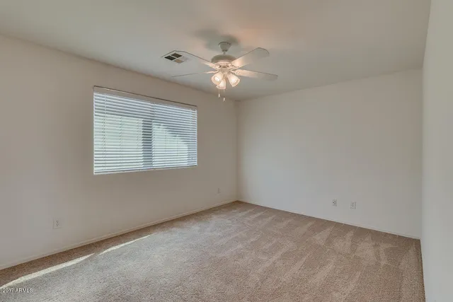 an empty room with a window and a fan