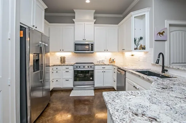 a kitchen with stainless steel appliances kitchen island granite countertop a sink stove and refrigerator