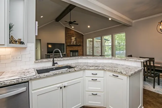 a kitchen with granite countertop a sink and white cabinets with wooden floor