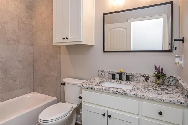 a bathroom with a granite countertop toilet sink and mirror
