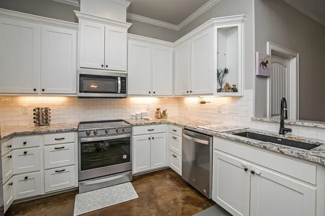 a kitchen with granite countertop white cabinets and stainless steel appliances
