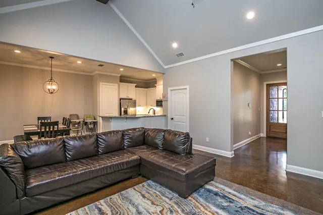 a living room with a couches and kitchen view with wooden floor