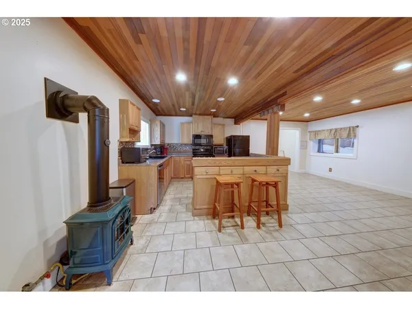 a kitchen with stainless steel appliances kitchen island granite countertop a refrigerator a stove a sink dishwasher and a microwave with wooden floor